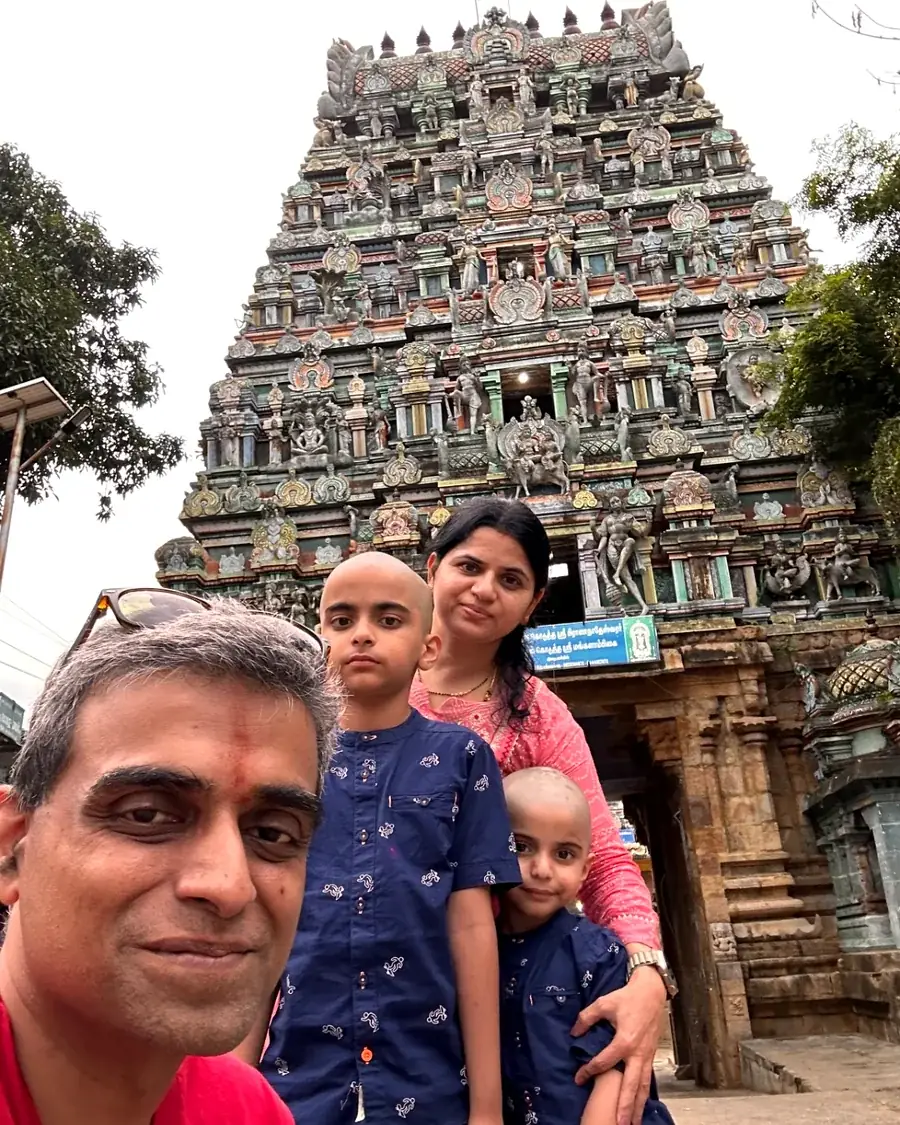 The family photographed beneath a tall painted temple gopuram