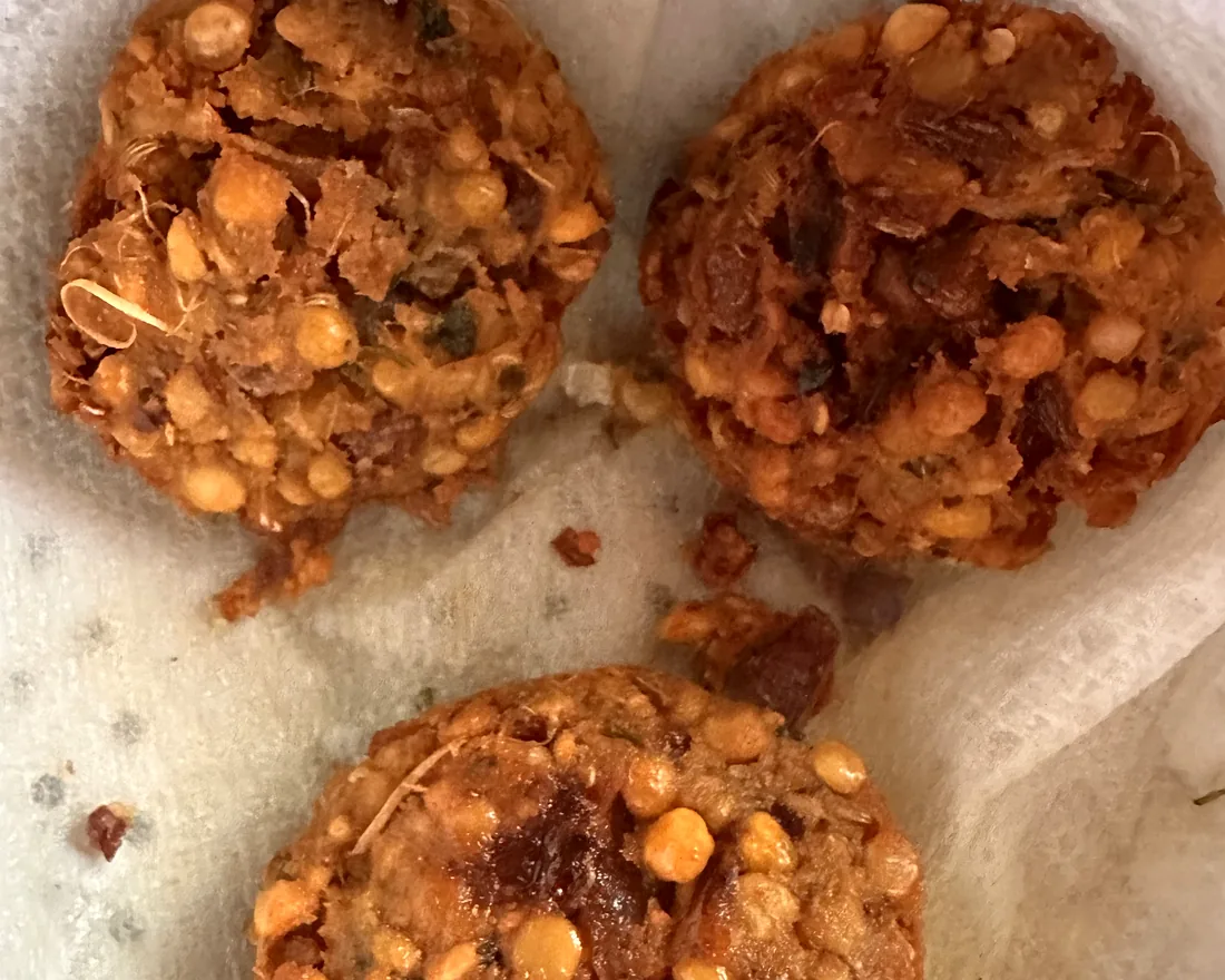 Three freshly fried masala vadai — crisp split-chana lentil fritters studded with onion and curry leaf — draining on paper