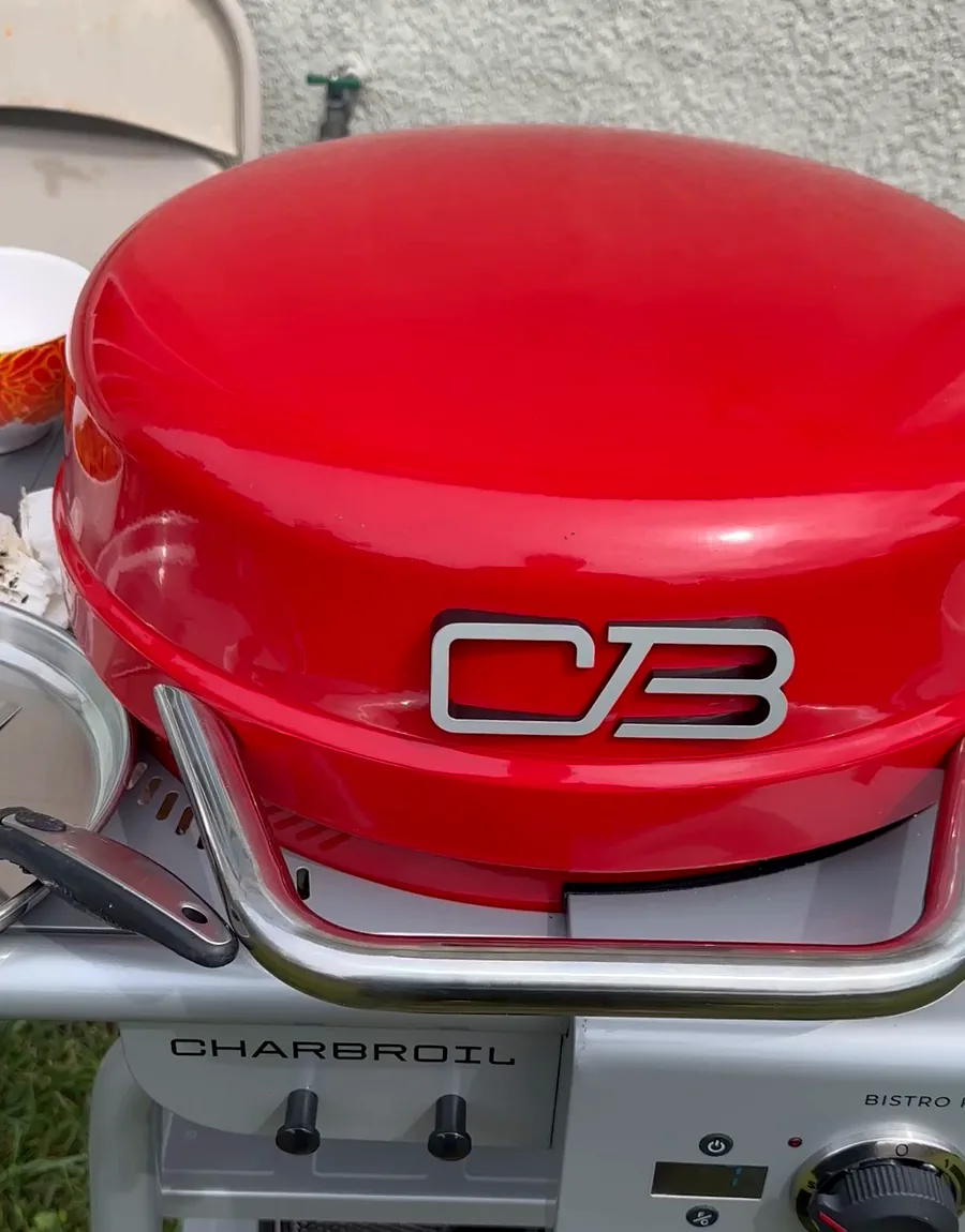 A red Char-Broil portable gas grill set up outdoors with prep bowls alongside